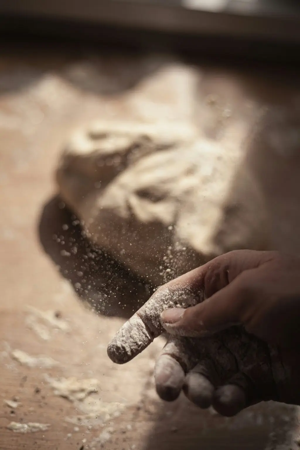 Homme étirant habilement la pâte à pizza dans une cuisine lumineuse, capture de son mouvement dynamique et de son expertise culinaire.